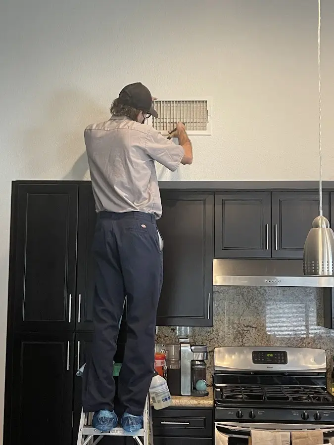 Technician inspecting an air vent during HVAC service in Hayesville